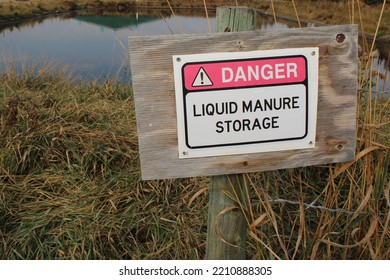 A Warning Sign Posted At The Edge Of A Large Livestock Manure Storage Lagoon