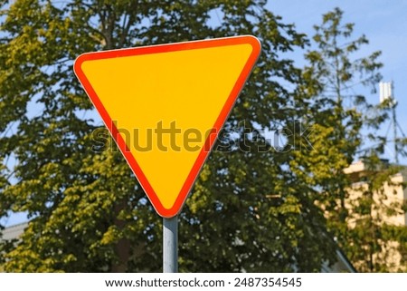 Warning sign in the shape of a triangle with a red border and a yellow centre requiring you to give way. Attention, you are approaching a priority road.