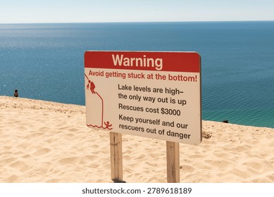 A warning sign urges caution on the steep slopes of Sleeping Bear Dunes National Seashore in Michigan.