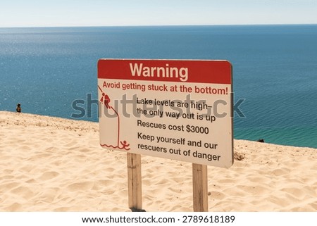 A warning sign urges caution on the steep slopes of Sleeping Bear Dunes National Seashore in Michigan.