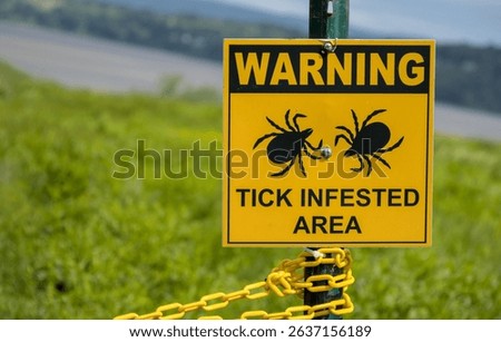 warning tick infested area sign in grassy area near the hudson river westchester county upstate new york (lyme disease carrying parasite insect bug)