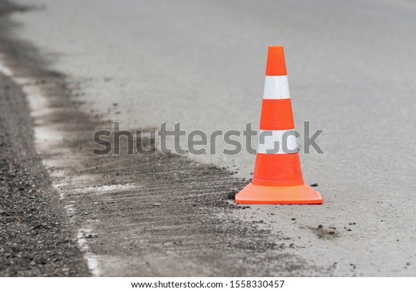 Warning traffic road cone stand on street\
asphalt city road during road restoration and road repairing,\
asphalt pavement works on\
highway.