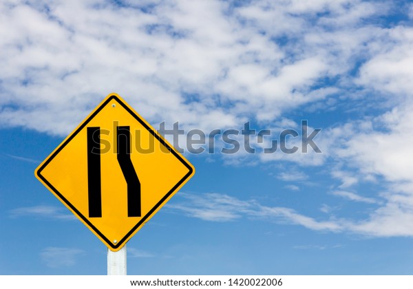 Warning traffic sign of narrow road ahead on\
blue sky background