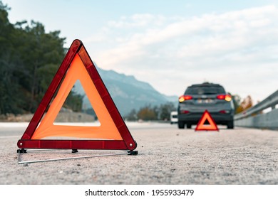 The warning triangle is at the back of the car at a safe distance.Car on the road behind warning triangle.The triangle placed behind the car. - Shutterstock ID 1955933479