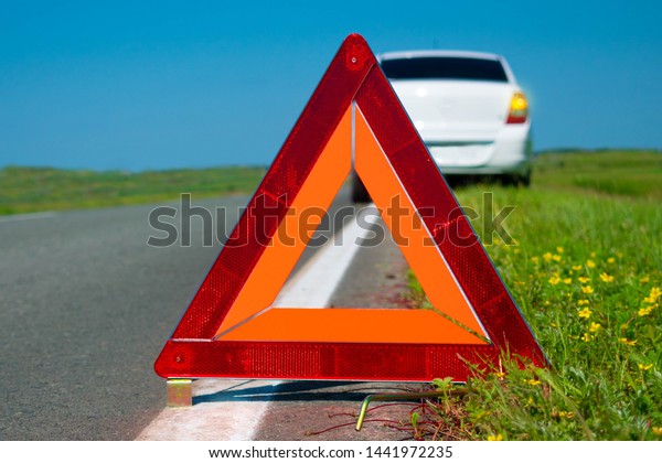 Warning triangle. Car breakdown on a\
country road. Malfunction of the car. Service\
maintenance.