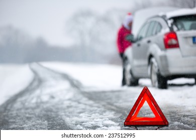 warning triangle with winter car breakdown in background 