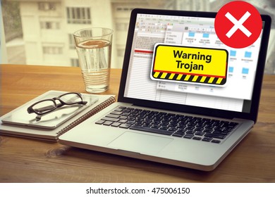 Warning Trojan Concept Computing Computer  Laptop with screen on table Silhouette and filter sun