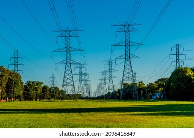 Warren, MI USA - September 29, 2021:  Horizontal, Long Shot Of Electric Power Lines At Dusk With A Clear Blue Sky And Grass And Trees.