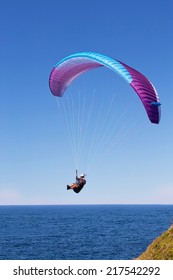 WARRIEWOOD,AUSTRALIA - SEPTEMBER 14, 2014: A man enjoys some time in the air, paragliding along the cliff tops above the beach in the spring sunshine.