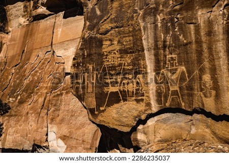 Warrior figures stand holding a severed head - part of the Mcconkie ranch petroglyphs created by the ancient Fremont culture, and located near the town of Vernal in northeastern Utah, United States.