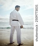 Warrior, karate and man at beach for exercise, training or thinking of martial arts outdoor. Fighter, person or practice taekwondo at ocean for fitness, sport or workout body with back view in summer