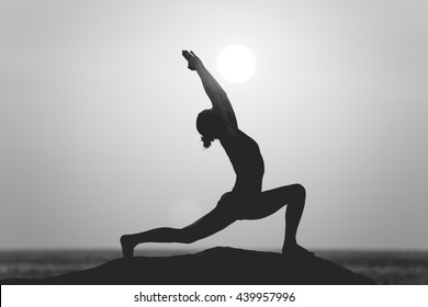 Warrior Pose From Yoga By Woman Silhouette On Sunset In Black And White Style Filter