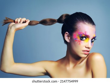 Warrior Queens Wear Makeup Like War Paint. Studio Shot Of An Attractive Young Woman With Brightly Colored Makeup Against A Blue Background.