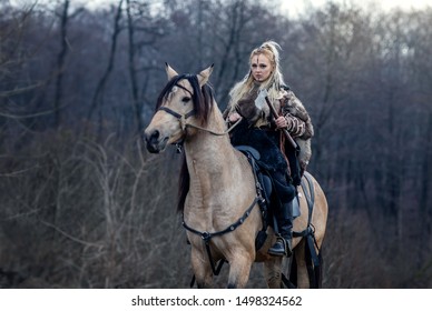 Warrior viking blonde female riding a horse in the woods - Medieval movie scene - Focus on the rider