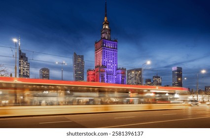  Warsaw Palace of Culture glows in red, white, and blue against the night sky, surrounded by modern skyscrapers. Light trails from passing cars and trams create a dynamic sense of motion - Powered by Shutterstock - Get 15% off with code: PIKWIZARD15
