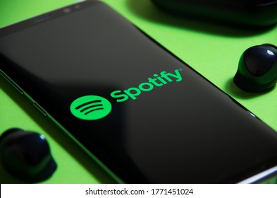 Warsaw, Poland - 10.06.2020: Spotify app on the smartphone. Music streaming. Surrounded by true wireless earbuds. Listening to music with Galaxy Buds - TWS.