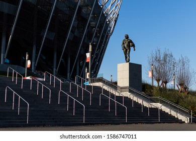 Warsaw Poland, 11/6/19: Statue Of The Polish Coach Kazimierz Gorski On The Pedestal At The Stone Steps With A Ball Walking In His Tracksuit Outside The National Stadium In Sunlight.