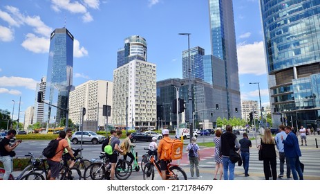 Warsaw, Poland. 23 June 2022. People of different ages and with comfortable clothes crossing the road through. View of a city street with residents, tourists and modern buildings.
