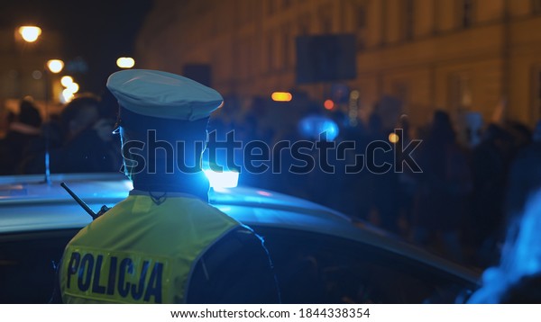 Warsaw, Poland\
30.10.2020 - Anti abortion and human rights protest, Womens strike,\
demonstrants passing near police car illuminated by emergency\
light. High quality\
photo