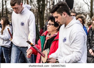 Warsaw, Poland - April 03, 2016: Two Young Boys With Torches Help An Elderly Woman, A Holocaust Survivor, Arrive At The Menorah Lit Spot, At A Ceremony In Memory Of Holocaust Victims