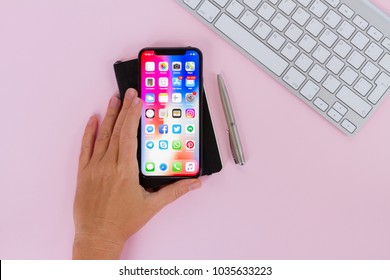 WARSAW, POLAND - DECEMBER 02, 2017: Someone hand holding New Iphone X mobile phone with cup of colorful apps icons