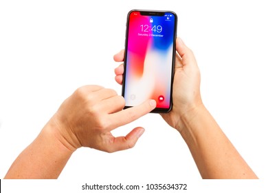 WARSAW, POLAND - DECEMBER 02: Two Hands Holding And Touching New Iphone X With Home Page Of Mobile Phone Over White Background
