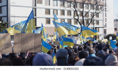 WARSAW, POLAND - FEBRUARY 27 2022: Demonstration, Protest Against The Russian War In Ukraine. Ukrainian Flag, Protesters Waving Flags, Posters And Banners Visible On The Shot. People In The Street