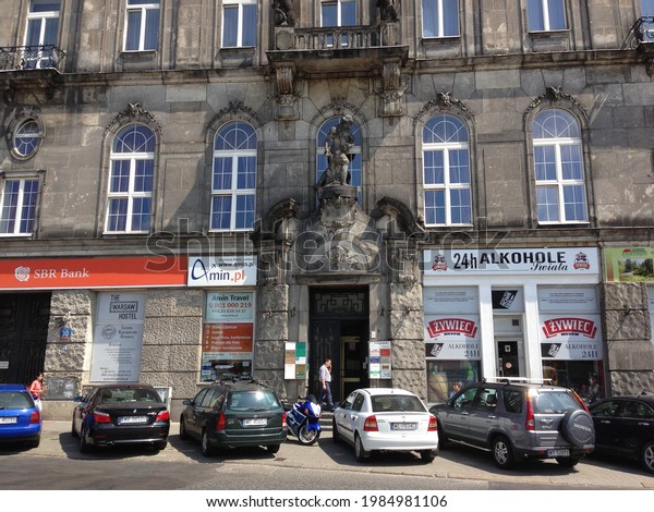 WARSAW, POLAND - JULY\
26 2013: Autos are parked in front of ornate entrance to building\
on Mikołaja Kopernika street, with SBR Bank and 24-hour Liquor\
Store on the ground\
floor.