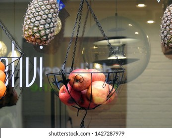 Warsaw, Poland - June 15, 2019: Pile Of Red Apples In A Metal Basket Hanged On The Exterior Of A Juice Bar With Assorted Fruits. Street Food Scene In Warsaw