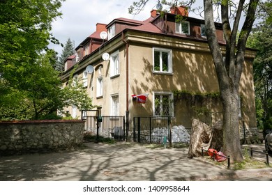 Warsaw, Poland - May 03, 2019: In The Saska Kepa District There Is A Multi-family House But It Is Not Too Big. There Are Many Trees Around And Next To It There Is A Sidewalk Along The Fence.