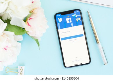 WARSAW, POLAND - MAY 13, 2018: New Iphone X Modern Mobile Phone With Facebook Page On Blue Desk With Flowers, Styled Flat Lay Scene