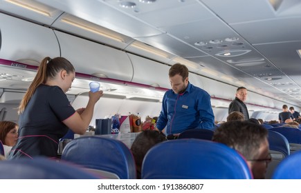 WARSAW, POLAND - OCTOBER 22, 2019: Wizzair Cabin Crew In Airplane. Departure From Warsaw To Roma, Italy. Serving Food And Beverages.