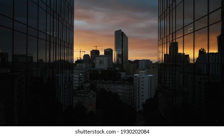 Warsaw skyline at night. Drone passing between two skyscrapers revealing red sky and silhouettes of the building in the distance. High quality photo - Powered by Shutterstock