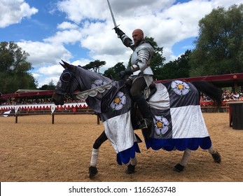 Warwickshire, UK - 13 August 2017: A knight holding up a sword in the air while riding a horse at a reenactment of the war of the roses at Warwick castle.