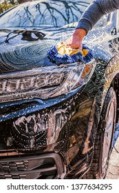 Wash A Car On A Sunny Day. Use A Brush And Soap To Wash A Car In The Driveway. Hand In Blurred Motion. 