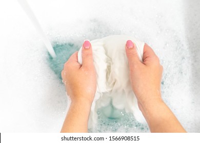 Wash clothing by hand with whitening detergent in laundry sink - Powered by Shutterstock