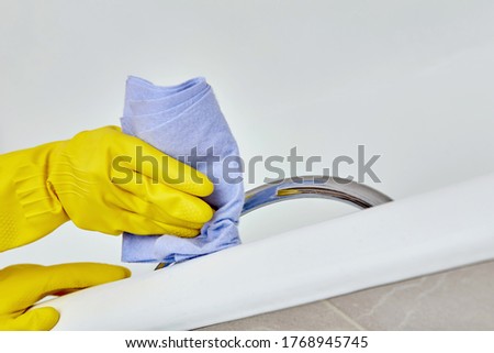 Wash the edge of the white bath. Daily routine at home. Gloves for cleaning.