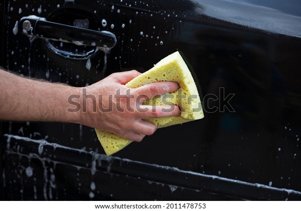 wash the fender of a black car with\
a washcloth on a sunny day in the garden after a\
flood,