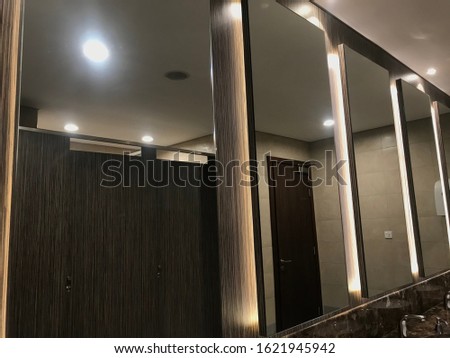 Wash room or Rest room interiors such as Beveled Type mirror and polished marble counter top wash basin and faucet setup for an male Toilet area of an Shopping mall