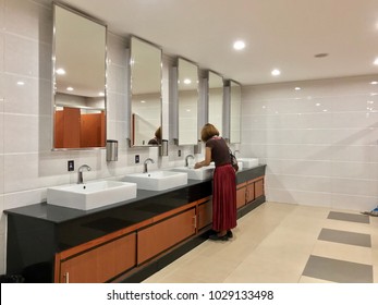 Wash Sink And Big Mirror In Public Toilet , Woman Washing Hand In Front Of The Mirror