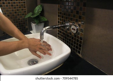 Wash Your Hands In A White Basin With An Automatic Faucet.