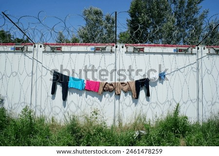 Washed clothes drying below barbed wire. Challenging living conditions in an improvised transit refugee camp at the Serbian and Hungarian border.