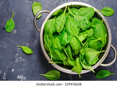 Washed fresh mini spinach in a colander on the old concrete table