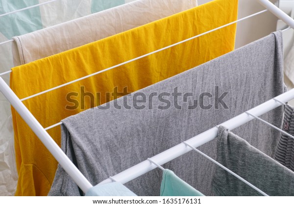 Washed laundry hanging on clothing dryer rack\
indoor. Close-up.