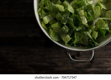 Washed Romaine Lettuce In Colander On Dark Wood Table