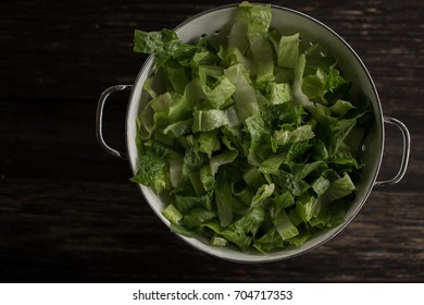 Washed Romaine Lettuce In Colander On Dark Wood Table