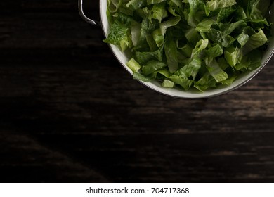 Washed Romaine Lettuce In Colander On Dark Wood Table