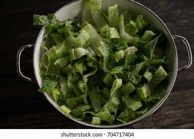 Washed Romaine Lettuce In Colander On Dark Wood Table