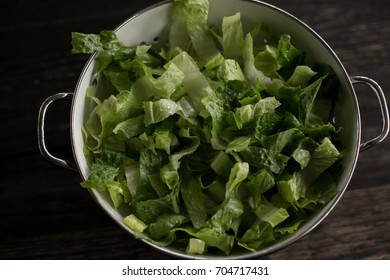 Washed Romaine Lettuce In Colander On Dark Wood Table