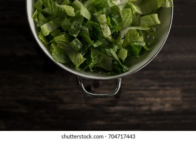 Washed Romaine Lettuce In Colander On Dark Wood Table